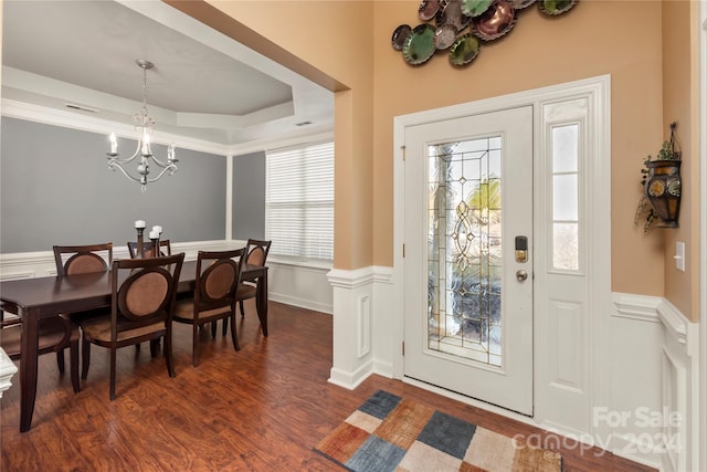 entrance foyer with a tray ceiling, a wealth of natural light, a chandelier, and dark hardwood / wood-style floors