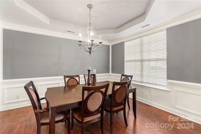 dining room featuring dark hardwood / wood-style flooring, a tray ceiling, ornamental molding, and a notable chandelier