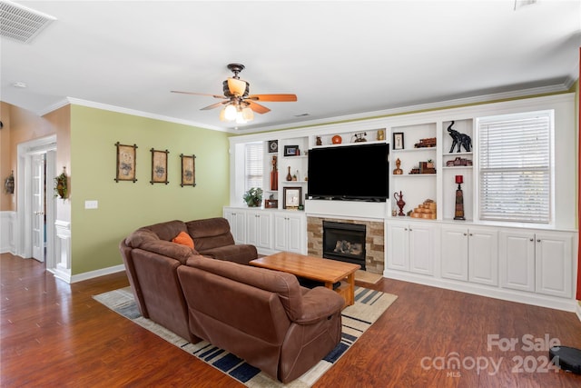 living room featuring ceiling fan, a stone fireplace, dark hardwood / wood-style flooring, and crown molding