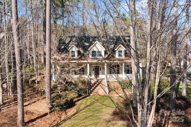 cape cod home with covered porch and a front yard