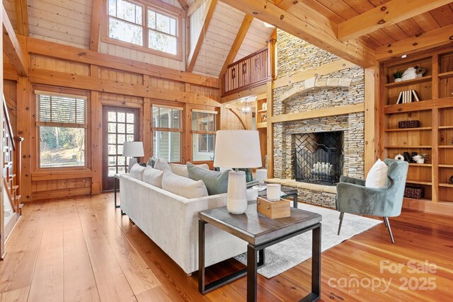 living room with a stone fireplace, wood ceiling, light hardwood / wood-style floors, and wood walls