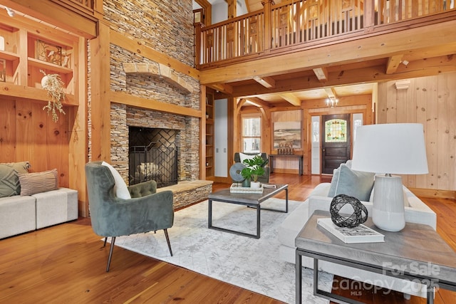 living room featuring hardwood / wood-style flooring, a high ceiling, a fireplace, and wooden walls