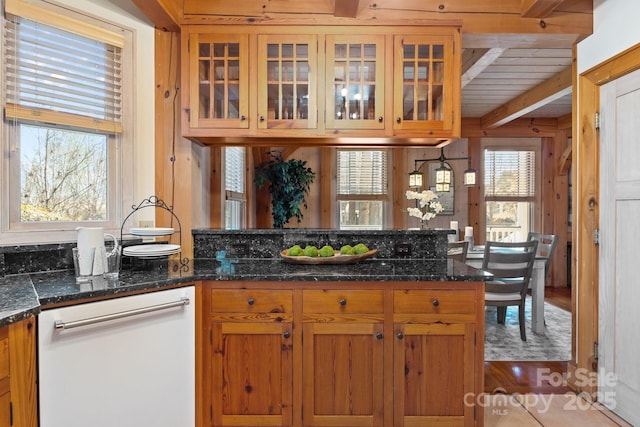 kitchen featuring dark stone countertops, hardwood / wood-style floors, beam ceiling, and white dishwasher