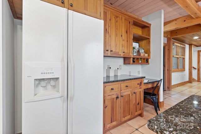 kitchen with light tile patterned floors, wood ceiling, beam ceiling, white refrigerator with ice dispenser, and dark stone counters