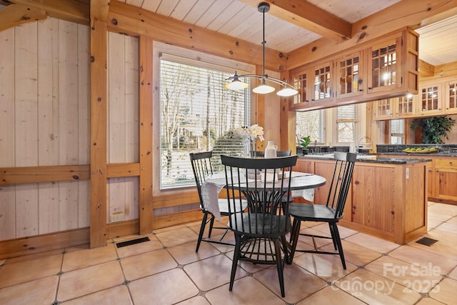 dining room with wood ceiling, beam ceiling, and wood walls