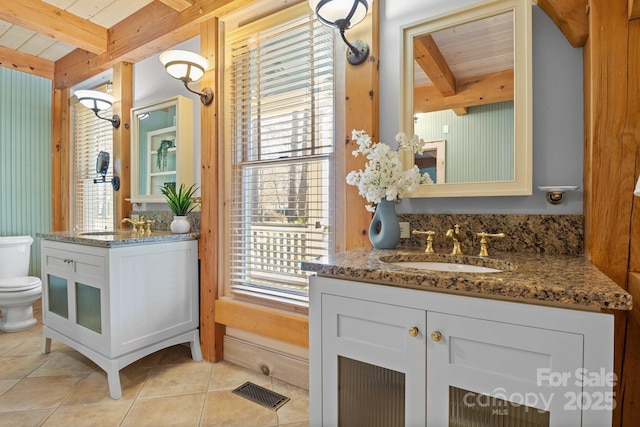 bathroom with beamed ceiling, plenty of natural light, and toilet