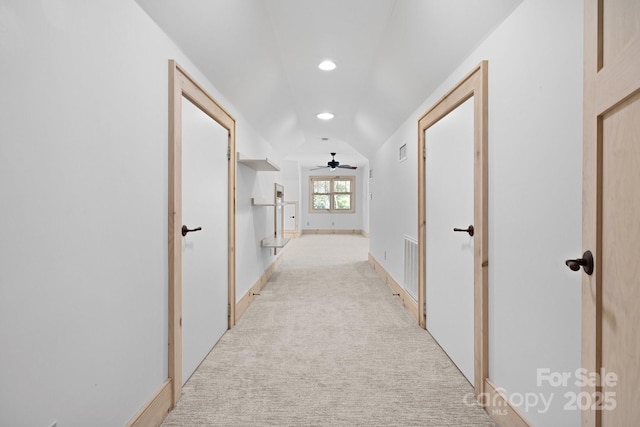 corridor featuring vaulted ceiling and light colored carpet