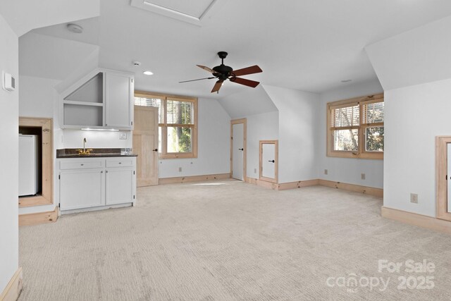 unfurnished living room with light carpet, sink, and vaulted ceiling