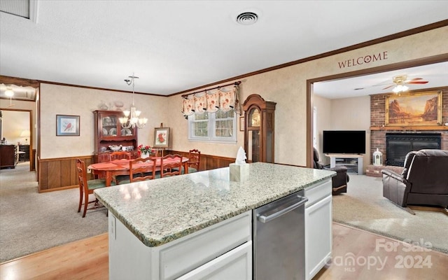 kitchen with white cabinets, light hardwood / wood-style flooring, a brick fireplace, decorative light fixtures, and a kitchen island