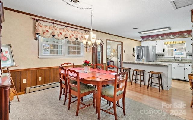 dining room featuring an inviting chandelier, a baseboard heating unit, sink, light wood-type flooring, and ornamental molding