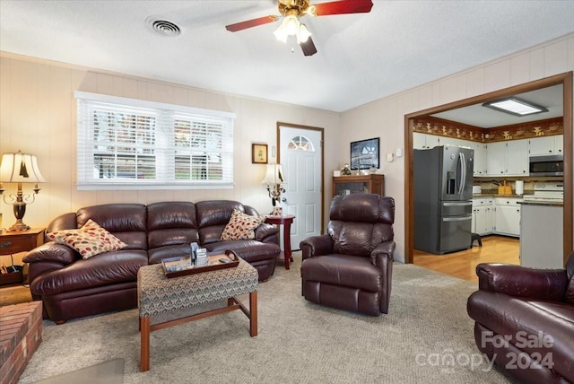 living room featuring ceiling fan and a textured ceiling