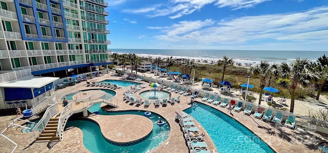 view of pool with a water view and a beach view