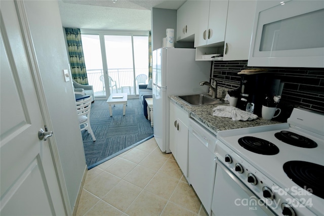 kitchen with white appliances, sink, decorative backsplash, light tile patterned floors, and white cabinetry