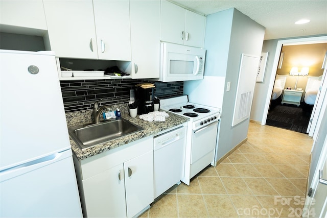 kitchen featuring tasteful backsplash, white appliances, sink, dark stone countertops, and white cabinetry