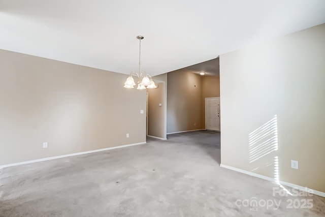 carpeted spare room with an inviting chandelier