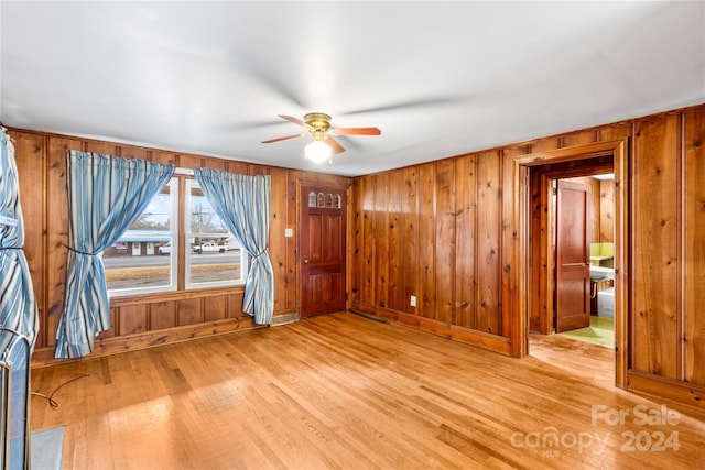 interior space featuring wooden walls, ceiling fan, and light wood-type flooring