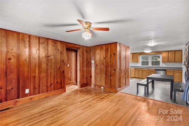 kitchen with wood walls, dishwasher, ceiling fan, and light hardwood / wood-style floors