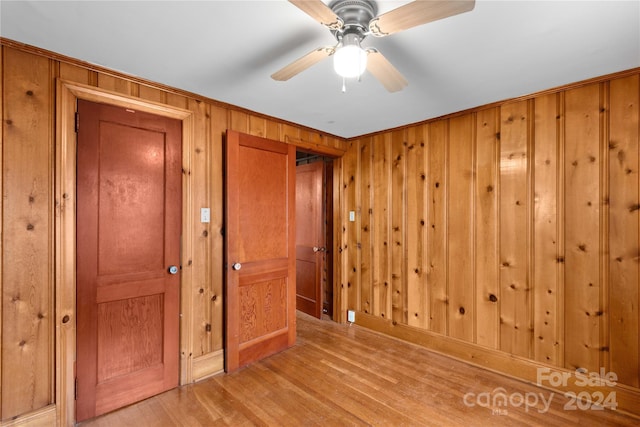 empty room featuring wood walls, ceiling fan, and light hardwood / wood-style floors