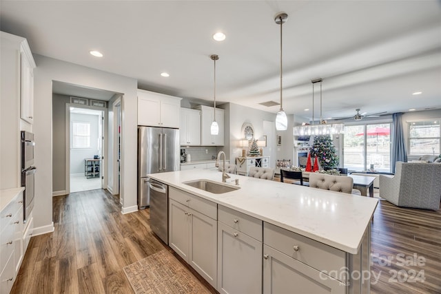 kitchen featuring sink, hanging light fixtures, a center island with sink, white cabinets, and appliances with stainless steel finishes