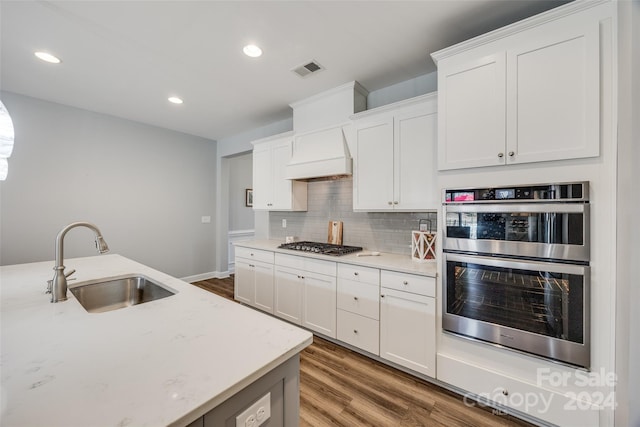 kitchen with light stone counters, stainless steel appliances, sink, hardwood / wood-style floors, and white cabinetry