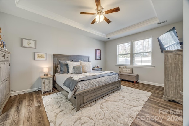 bedroom with hardwood / wood-style flooring, ceiling fan, and a tray ceiling