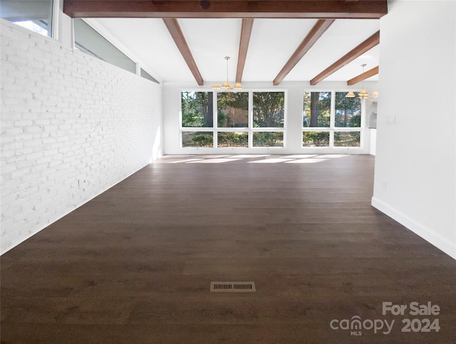 unfurnished living room featuring vaulted ceiling with beams, dark hardwood / wood-style floors, brick wall, and a chandelier