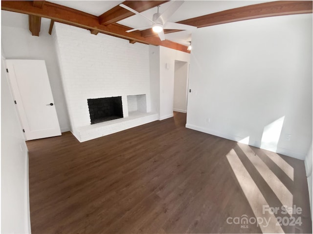 unfurnished living room with ceiling fan, a fireplace, beamed ceiling, and dark hardwood / wood-style floors