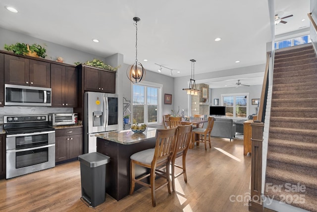 kitchen with stainless steel appliances, decorative backsplash, light wood-style flooring, and dark brown cabinets