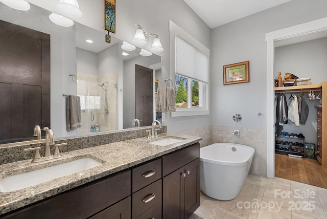 bathroom with a sink, a shower stall, a freestanding bath, and double vanity