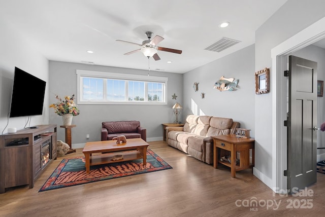 living room featuring visible vents, ceiling fan, baseboards, and wood finished floors