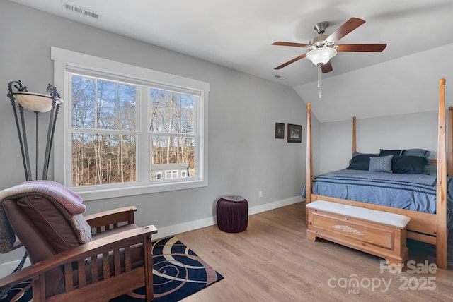 bedroom featuring lofted ceiling, visible vents, baseboards, and wood finished floors