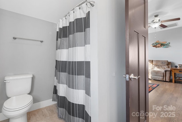 full bathroom with a ceiling fan, a shower with shower curtain, toilet, and baseboards