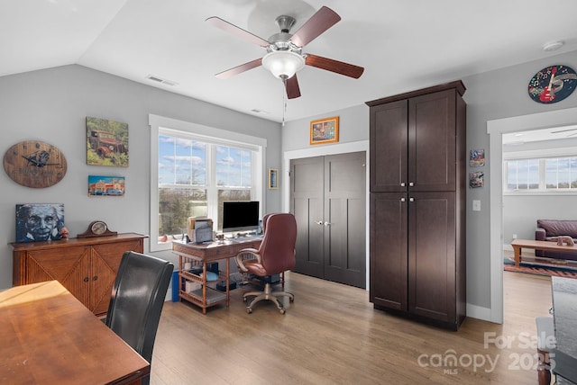 office space featuring lofted ceiling, light wood-style flooring, visible vents, and a ceiling fan