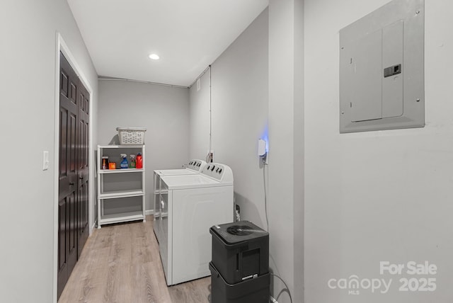 clothes washing area featuring washing machine and dryer, recessed lighting, laundry area, light wood-type flooring, and electric panel