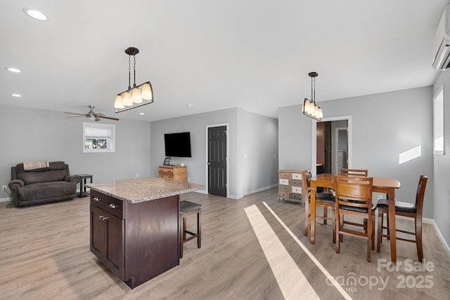 kitchen featuring a center island, light wood-style floors, open floor plan, dark brown cabinetry, and baseboards