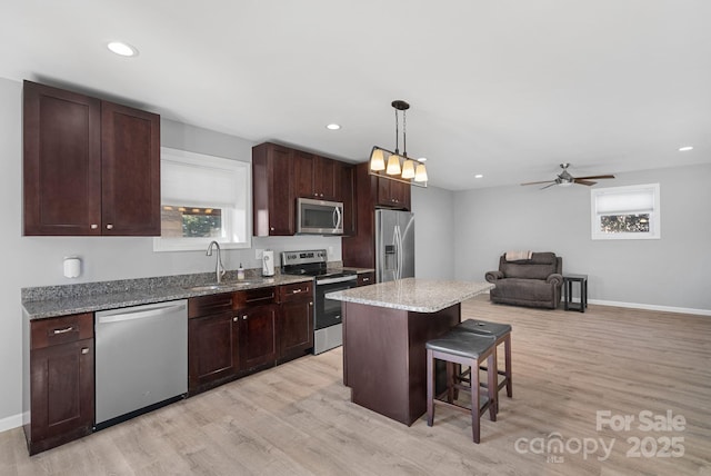 kitchen featuring appliances with stainless steel finishes, light wood-type flooring, a sink, and a breakfast bar area