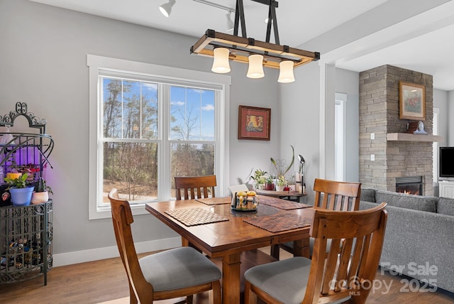 dining space with a fireplace, plenty of natural light, wood finished floors, and baseboards