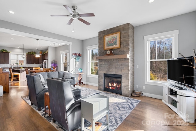 living area featuring recessed lighting, light wood-type flooring, a fireplace, and baseboards