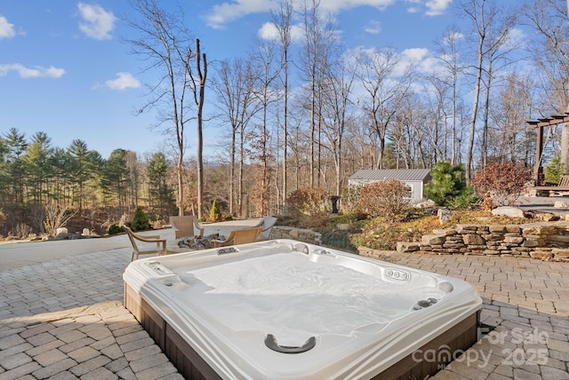 view of patio / terrace with an outdoor hot tub and an outdoor structure