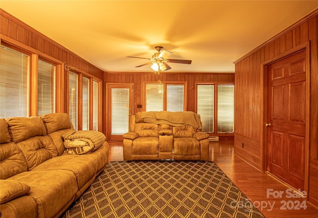 living room featuring hardwood / wood-style flooring, ceiling fan, and wooden walls