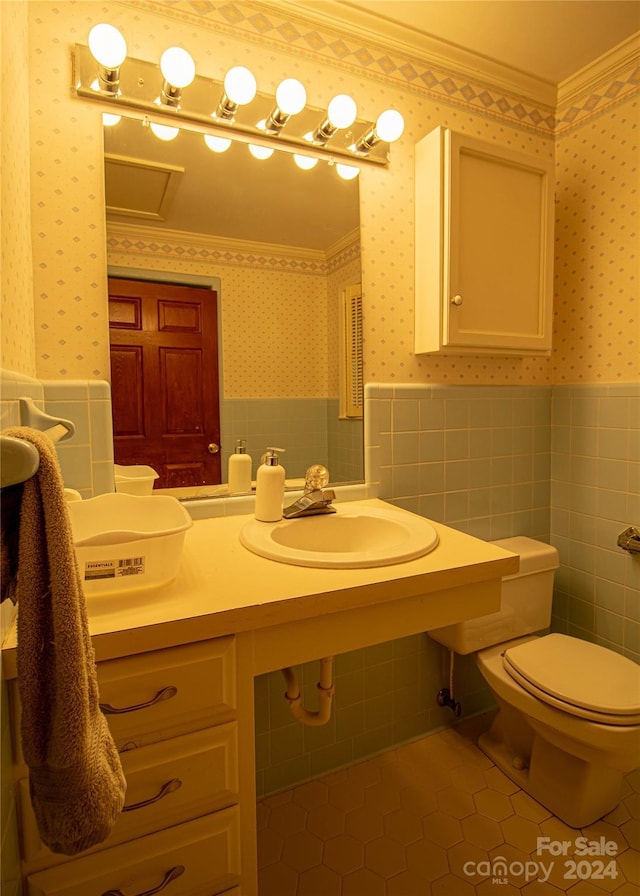 bathroom with tile patterned floors, ornamental molding, sink, tile walls, and toilet