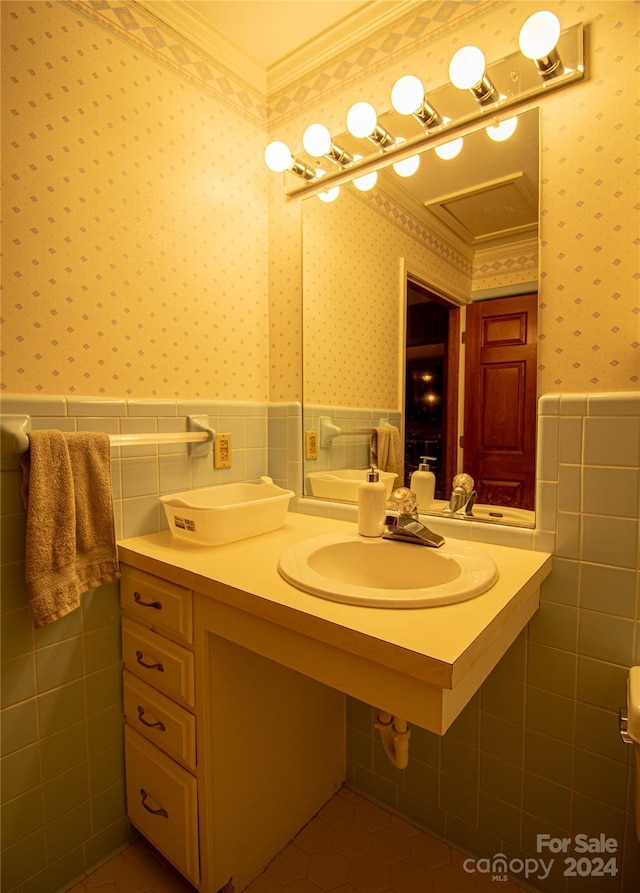 bathroom featuring tile walls, ornamental molding, and sink