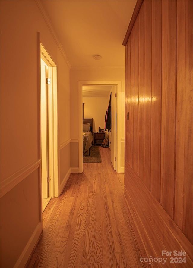 hall with light hardwood / wood-style floors and ornamental molding