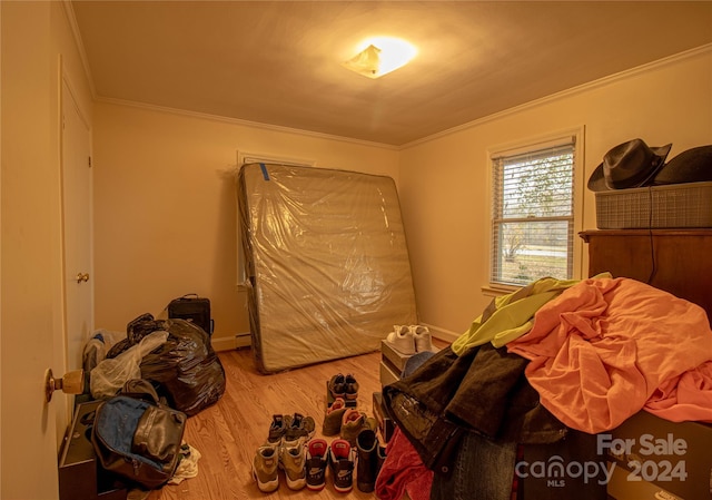 bedroom with baseboard heating, crown molding, and hardwood / wood-style floors