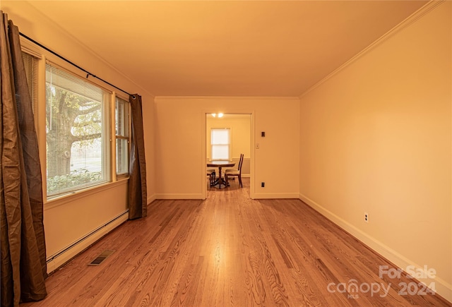 spare room with light wood-type flooring, a baseboard radiator, plenty of natural light, and crown molding