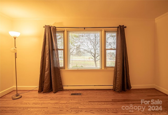 interior space with hardwood / wood-style floors, a baseboard radiator, and crown molding