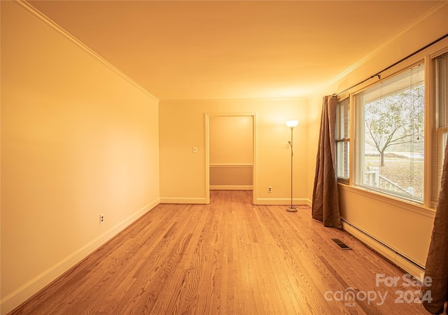 spare room with light hardwood / wood-style floors, baseboard heating, and ornamental molding