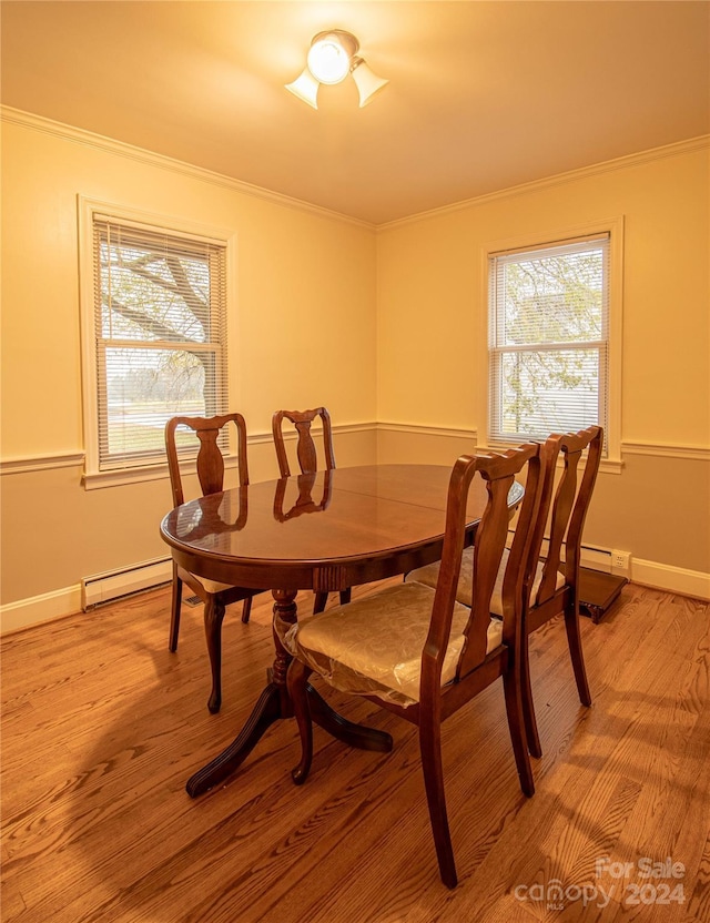 dining area with light hardwood / wood-style floors, crown molding, and baseboard heating