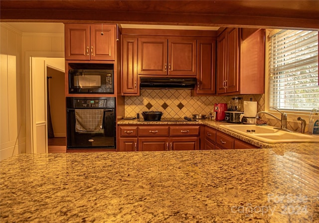 kitchen with light stone countertops, sink, tasteful backsplash, and black appliances