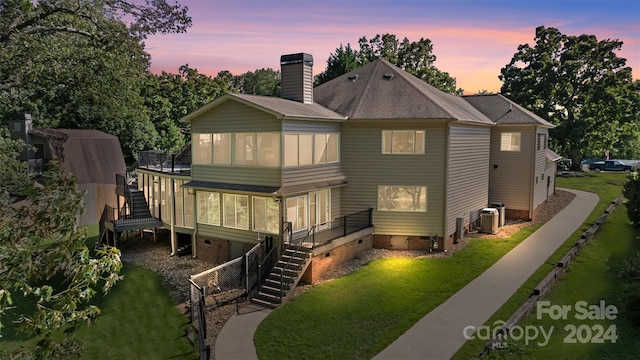 back house at dusk with a sunroom and a yard